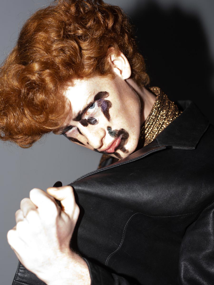 Man withe red hair and black make up wearing a leather jacket