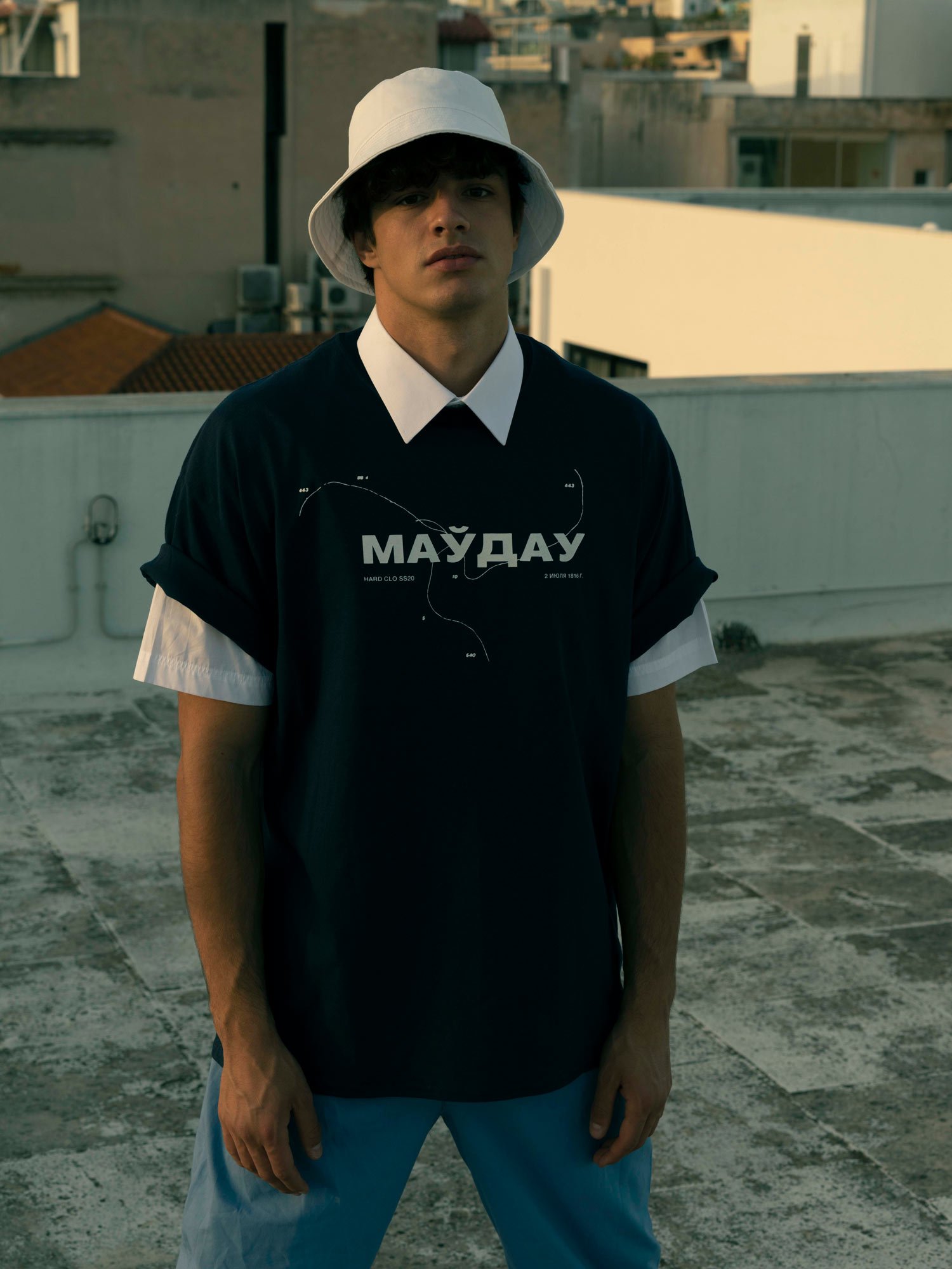 Man on a rooftop wearing a white bucket hat