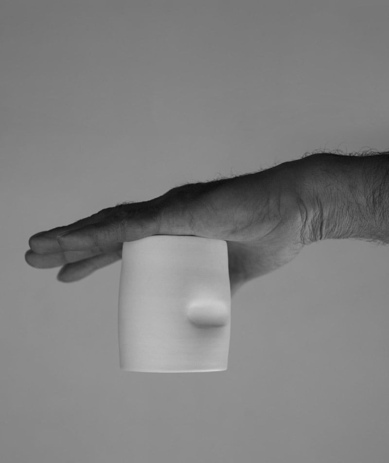 A hand holding a white cup upside down