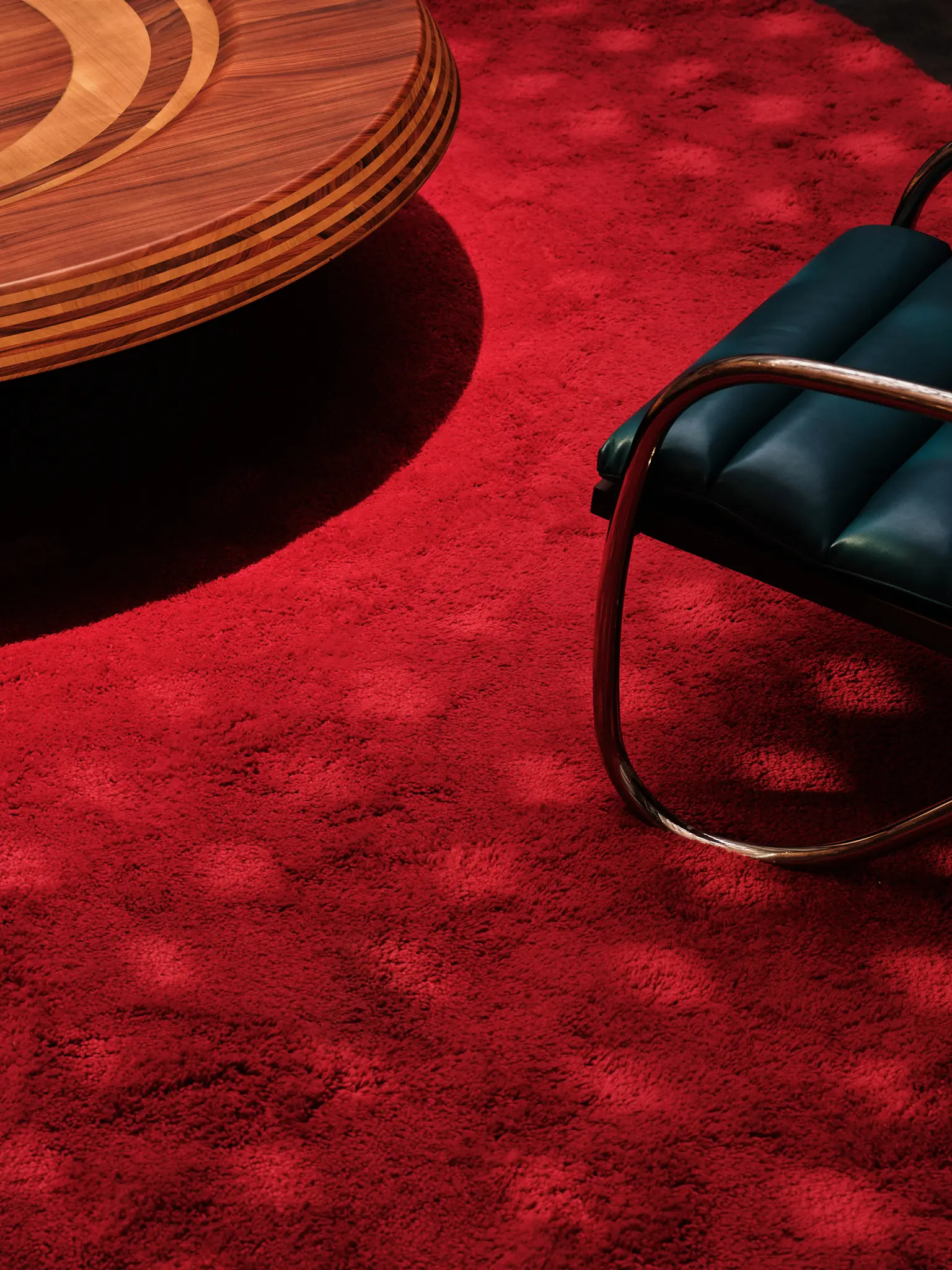 Charlotte Perriand Furniture Detail — Saint Laurent Detail of a wooden table and red carpet in the Saint Laurent Charlotte Perriand installation