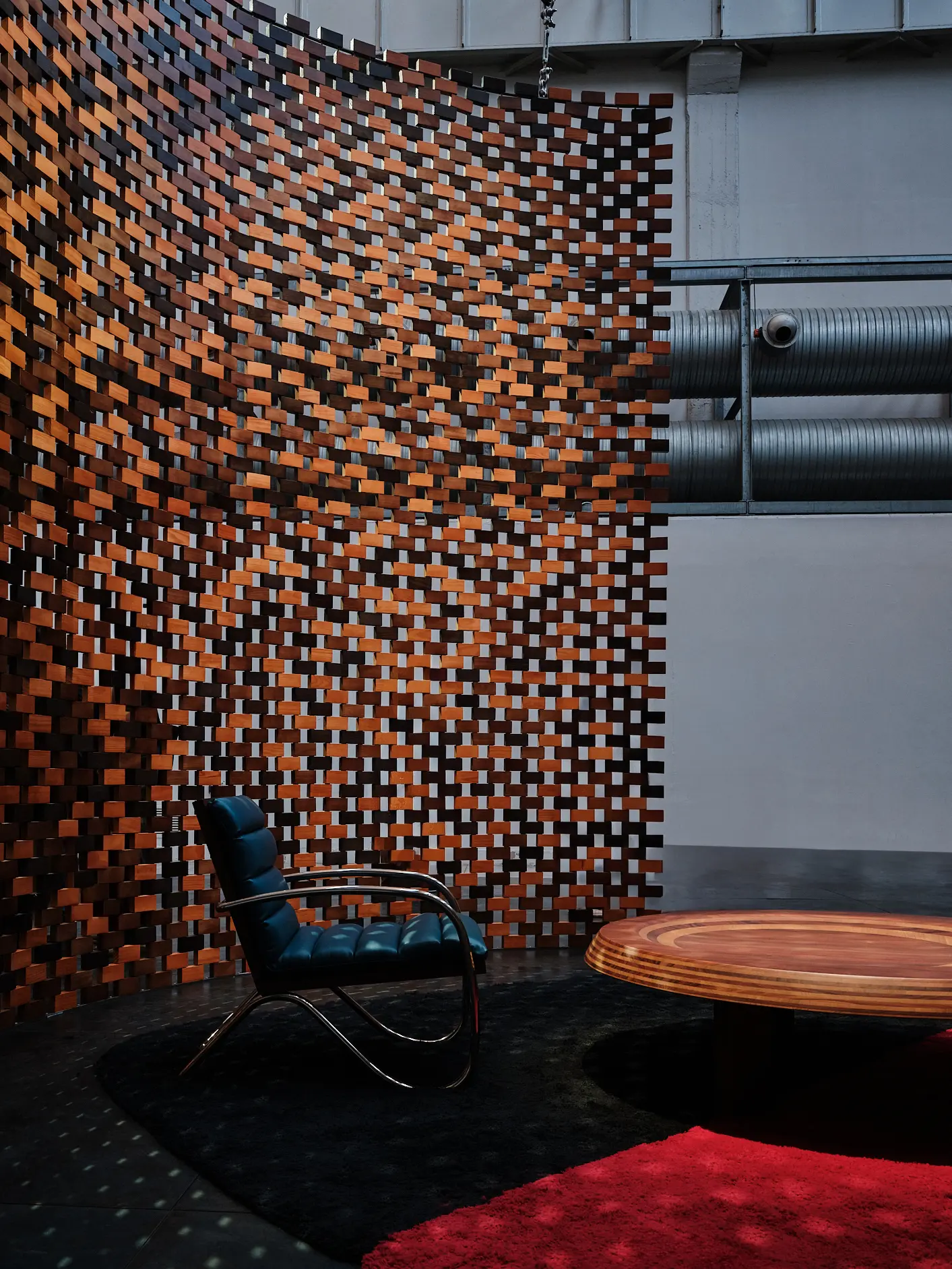 Charlotte Perriand Seating — Saint Laurent Exhibition Chair and table placed against a curved woven wall in the Saint Laurent Charlotte Perriand installation